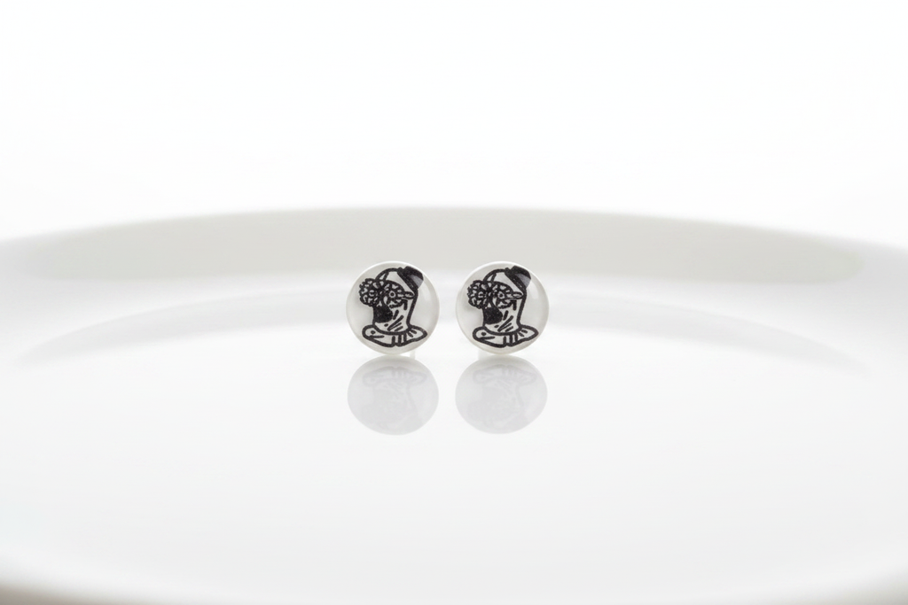 Round white stud earrings with black illustrated character design